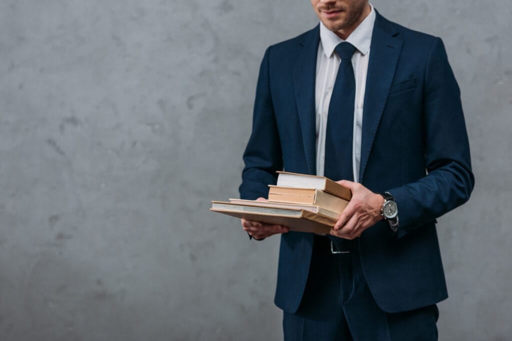 cropped shot of businessman holding stack of books 