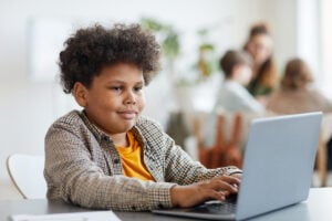 Young boy working on a laptop about online safety and child protection.