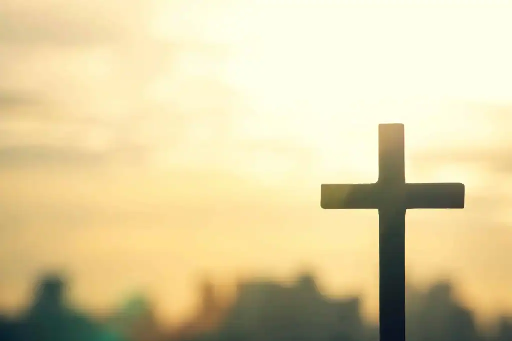 Cross symbol against a sunset sky, representing faith and hope.